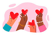 Hearts in hands of people different races symbolize kindness and charity towards ethnic minorities