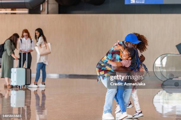 dark-skinned man holding his two little daughters that are just arriving at the airport terminal - running up an escalator stock pictures, royalty-free photos & images