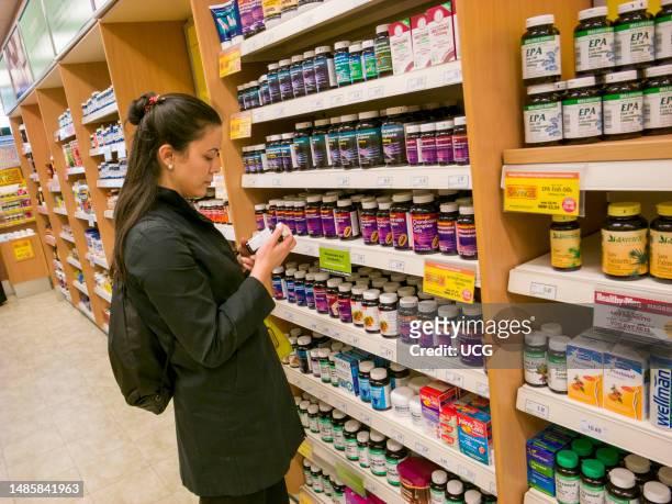 Woman shopping for multi-vitamins in Holland and Barrett shop, London, UK.
