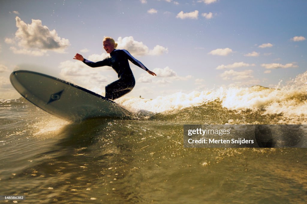 Girl on longboard surfboard on wave.