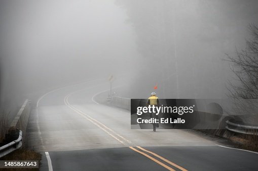 In Silhouette Bicyclist on Foggy Country Road Bridge