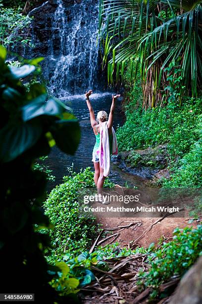 woman standing near waterfall on trail to queens bath. - princeville stock pictures, royalty-free photos & images