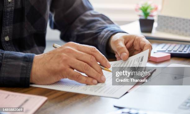 close-up of a man holding a tax form, working from home - skatt bildbanksfoton och bilder