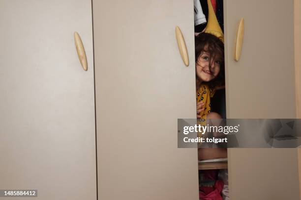 little girl playing in the wardrobe - kid hide and seek stock pictures, royalty-free photos & images