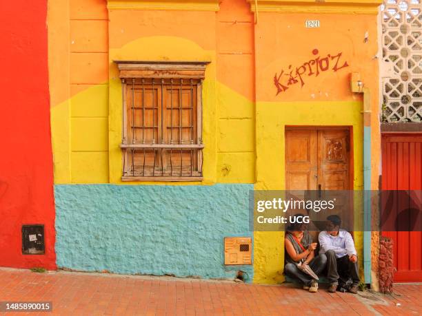 Young people talking in s street doorway in La Candelaria district, Bogota, Colombia.