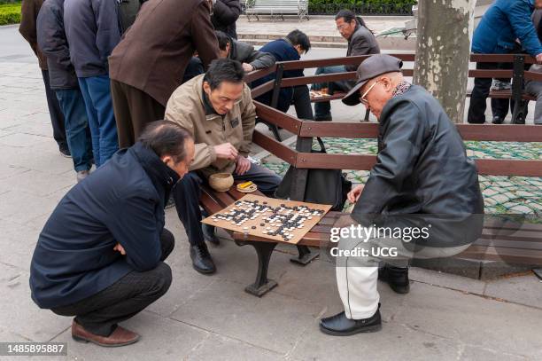 Men playing the ancient strategy board game of Go in Fuxing Park, Shanghai, China.