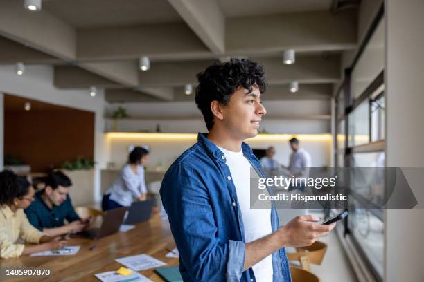 geschäftsmann benutzt sein handy, während er in einem coworking-büro arbeitet - internship marketing stock-fotos und bilder