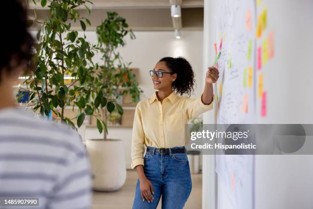 mujer haciendo una presentación de negocios a su equipo en la oficina - reunion de personal fotografías e imágenes de stock