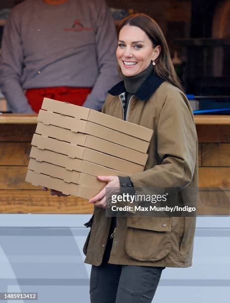 Catherine, Princes of Wales carries takeaway pizza boxes, collected from a pizza van, as she visits Dowlais Rugby Club on April 27, 2023 in Merthyr...