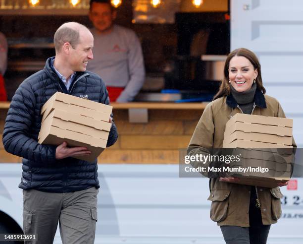 Prince William, Prince of Wales and Catherine, Princes of Wales carry takeaway pizza boxes, collected from a pizza van, as they visit Dowlais Rugby...