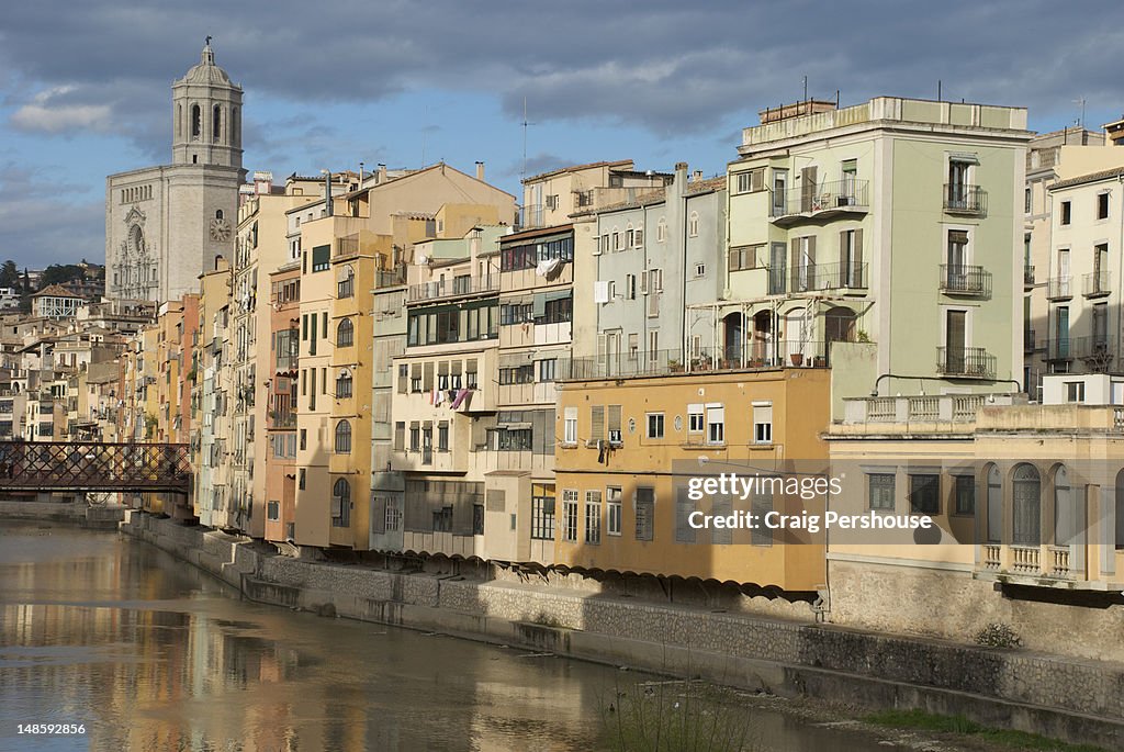 Colourful buildings by the Onyar River with Cathedral behind.