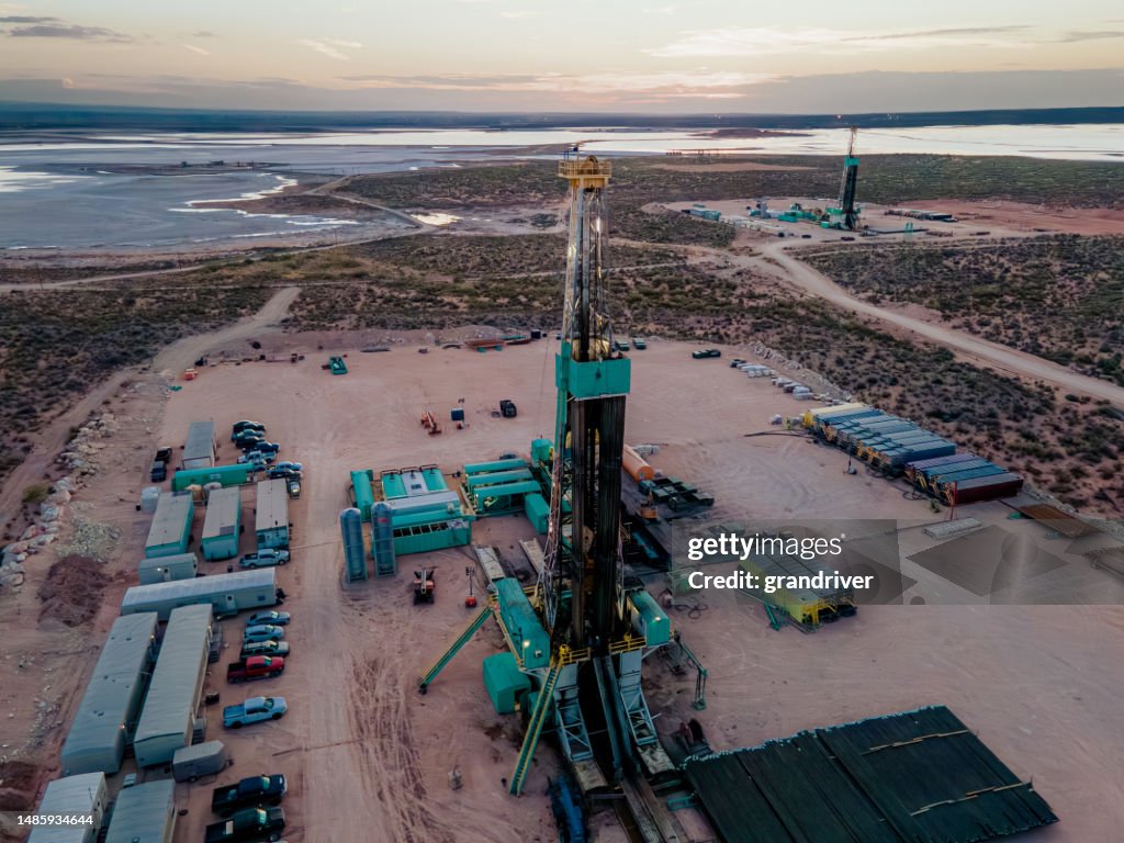 Drone captura una impresionante puesta de sol sobre la cuenca del Pérmico, mostrando una plataforma petrolera perforando y fracturando el fracking en busca de petróleo, en medio de la inmensidad del paisaje