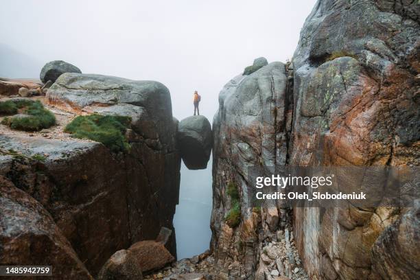 woman standing on kjeragbolten - contradiction stock pictures, royalty-free photos & images
