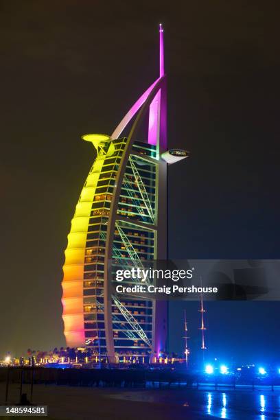 burj al-arab hotel colourfully illuminated at night. - burj al arab night stock pictures, royalty-free photos & images