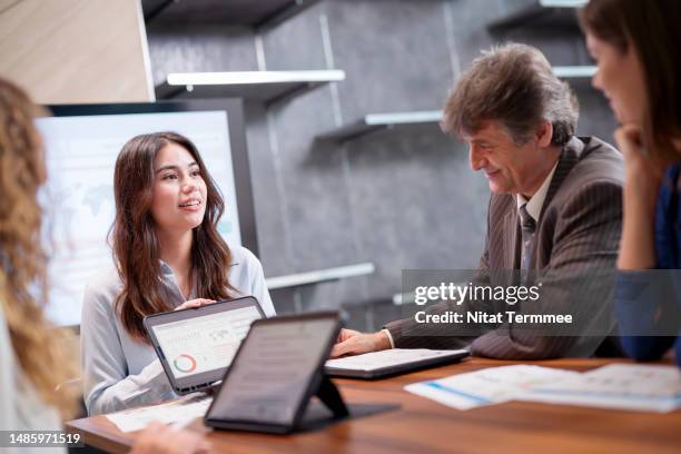 share constructive feedback in project management with team members. a female project leader sharing and presenting timeline progress with a team over a tablet computer in a business office. - better decisions stock pictures, royalty-free photos & images