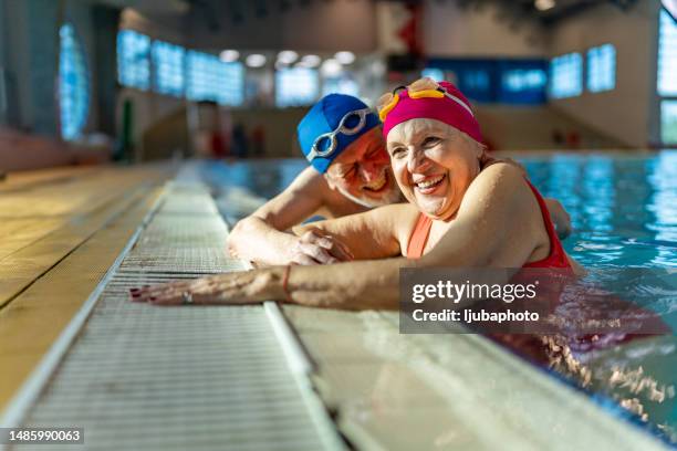 two senior friends hanging out together in the swimming pool. - 80 plus years imagens e fotografias de stock
