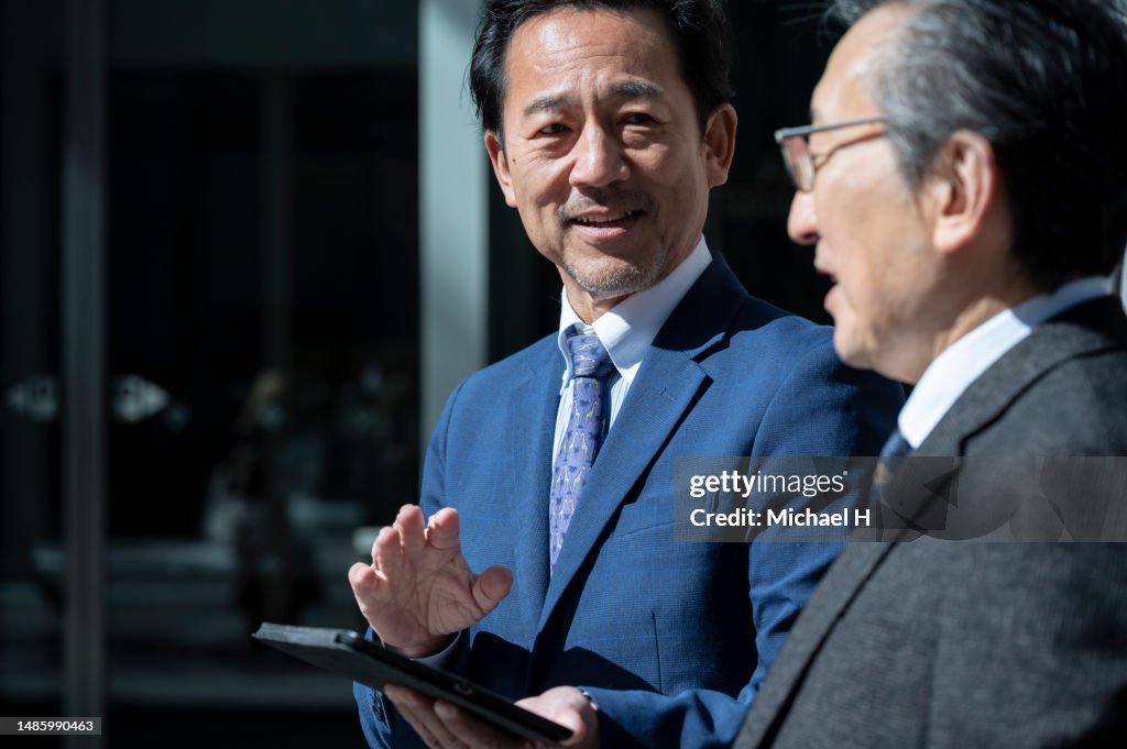 Mature Office workers having a meeting using a digital tablet.
Talking outside the office.