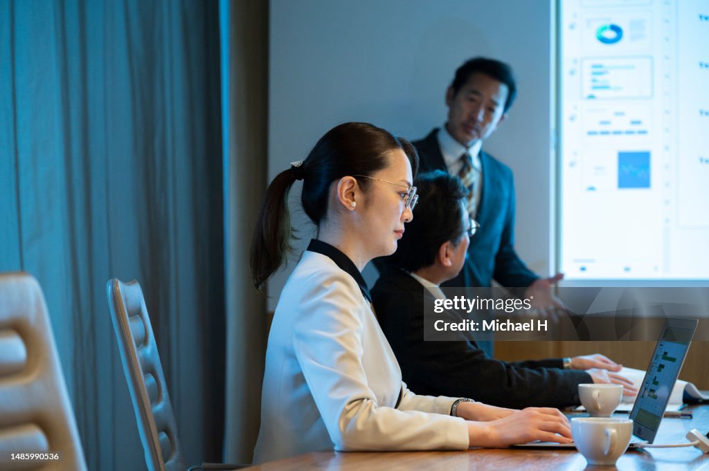 Businesswoman attending a meeting while using a laptop