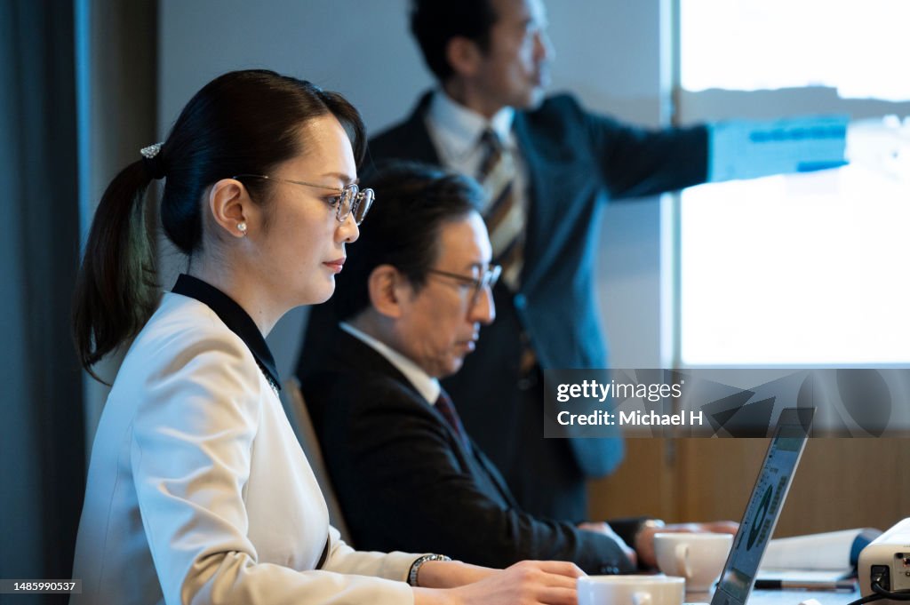 Businesswoman attending a meeting while using a laptop