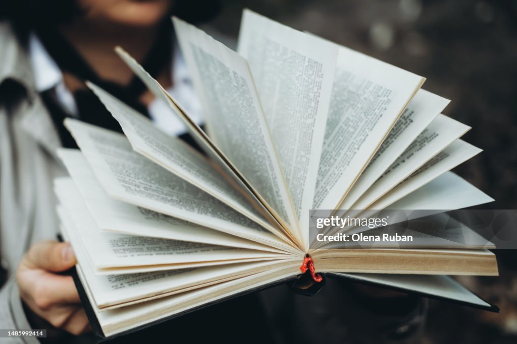 A person holding a book with fanned pages.