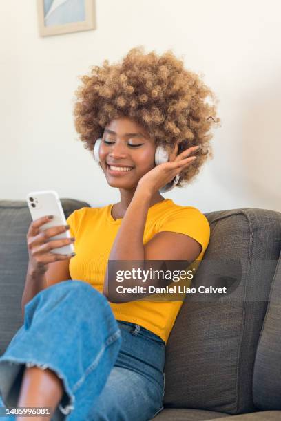 young woman listening to headphones and looking at a smartphone - auriculares stock pictures, royalty-free photos & images