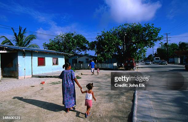 mother and daughter walking past house, d.u.d muicipality. - islas marshall fotografías e imágenes de stock