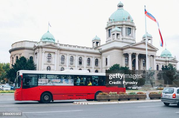 ein roter bus vor dem gebäude des serbischen nationalparlaments - serbian flag stock-fotos und bilder