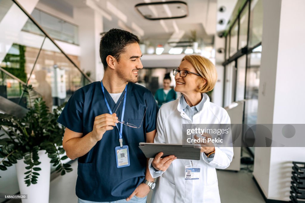 Oberärztin im Gespräch mit ihrer jungen Kollegin auf dem Krankenhausflur