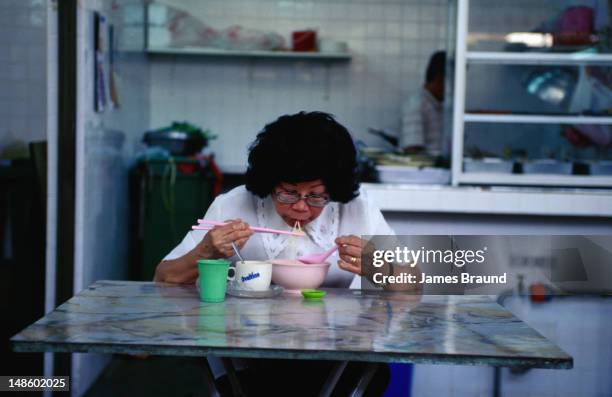 woman eats early morning laksa. - laksa imagens e fotografias de stock