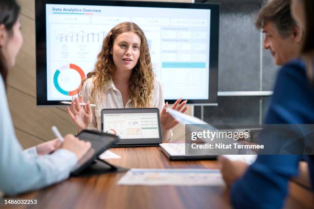 a new-product development and product life-cycle strategies to to increase sales growth. product development manager using a tablet computer to discuss a new product market and life cycle ideas with her team in a business office. - ciclo de vida imagens e fotografias de stock