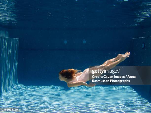 young girl swims in blue swimming pool in swimsuit and googles - girls flashing camera stock-fotos und bilder