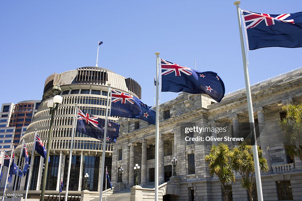 New Zealand flags flying in front of the Beehive and New Zealand's Parliament House.