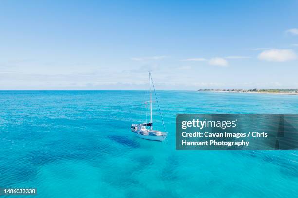 aerial of sailboat anchored in turquoise blue water in bimini, bahamas - bimini fotografías e imágenes de stock