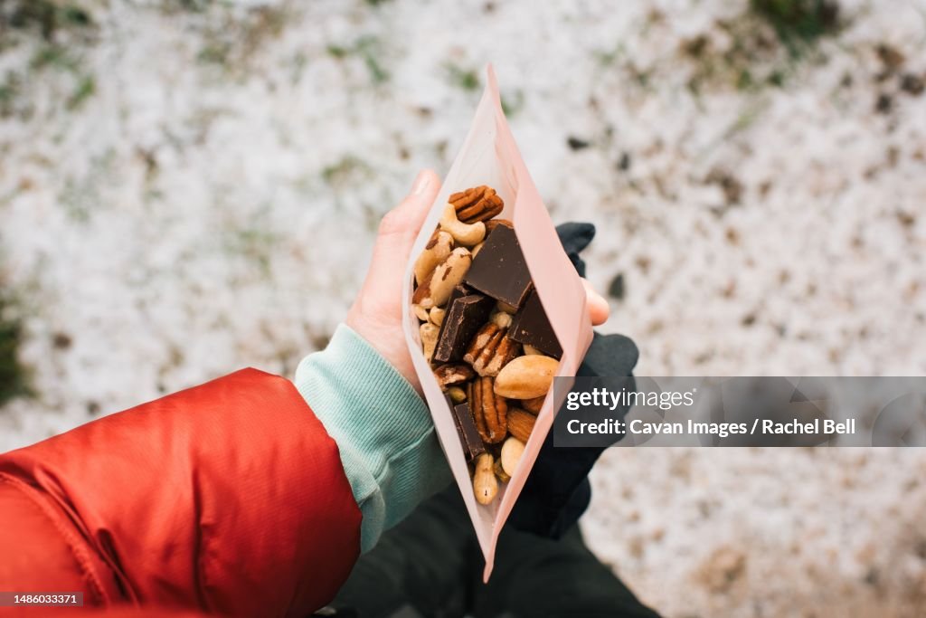 Woman holding trail mix in a reusable snack bag whilst hiking