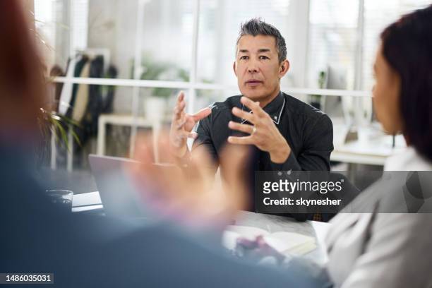 asian manager talking to his colleagues on a meeting in the office. - ceo stock pictures, royalty-free photos & images