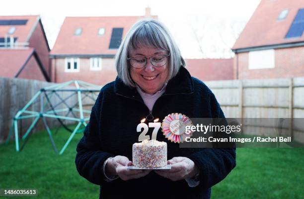 lady celebrating her 72nd birthday with a cake and candles - day anniversary stock pictures, royalty-free photos & images