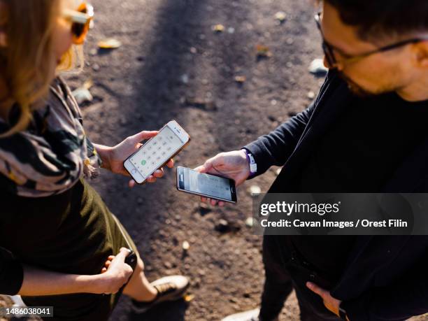 man and a young blonde are exchanging phones in the park - cheater stock pictures, royalty-free photos & images