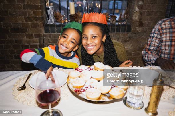 kinder in weihnachts-cracker-hüten mit mince pies - kompatibilität stock-fotos und bilder