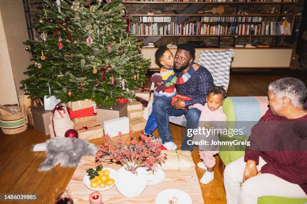 young son giving father christmas present, hug, and kiss - pinaceae stock pictures, royalty-free photos & images