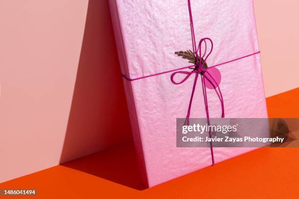 pink gift box on orange background (its a book) - birthday wrapping paper stock pictures, royalty-free photos & images