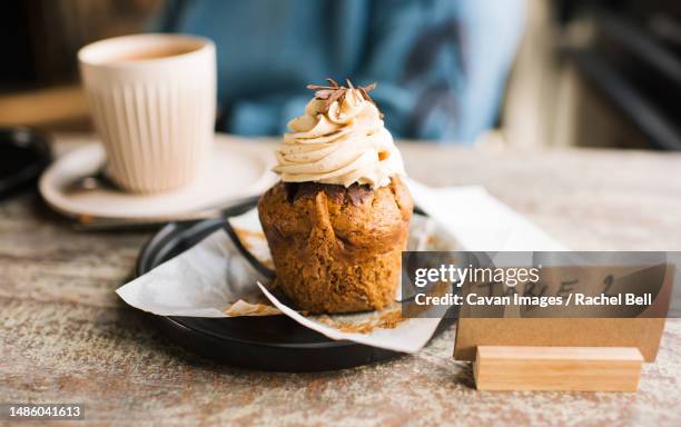 unwrapped cupcake on a table in a cafe with coffee - winchester england stock-fotos und bilder