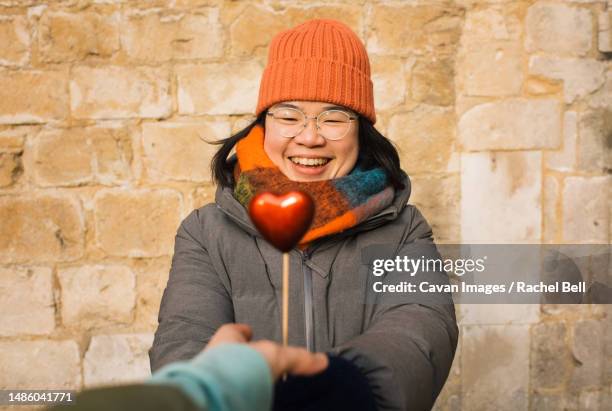 asian woman happily receiving a red heart for valentines - winchester england stock pictures, royalty-free photos & images