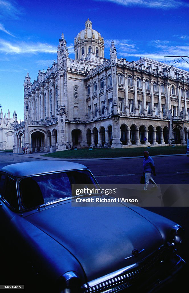 An old car parked across the street from the National Capital Building.