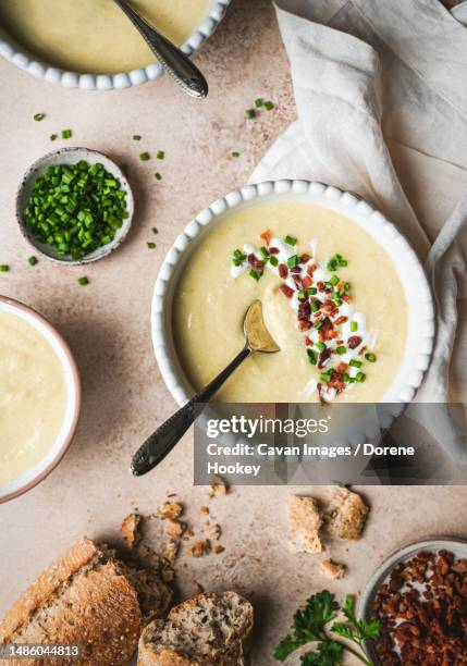 bowls of potato leek soup and bread on beige background from above - poireau photos et images de collection