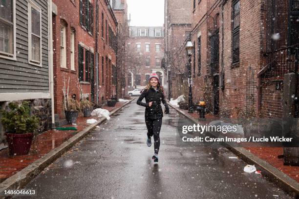 college girl running in snowstorm - boston winter stock pictures, royalty-free photos & images