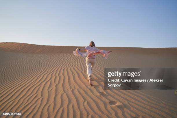 happy woman runs on a sand dune while on vacation - abu dhabi sunrise stock pictures, royalty-free photos & images