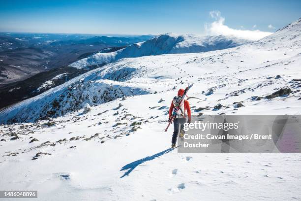 ski mountaineer walking through frozen snow field on mountain - new hampshire stock pictures, royalty-free photos & images