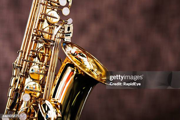 shiny bright saxophone in close up against brown background - saxophone stock pictures, royalty-free photos & images