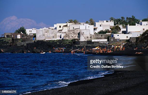 black volcanic sand and white washed buildings on beach. - stromboli stock-fotos und bilder
