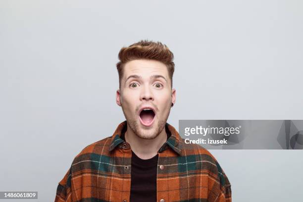 surprised young man looking at camera - surprised face stock pictures, royalty-free photos & images